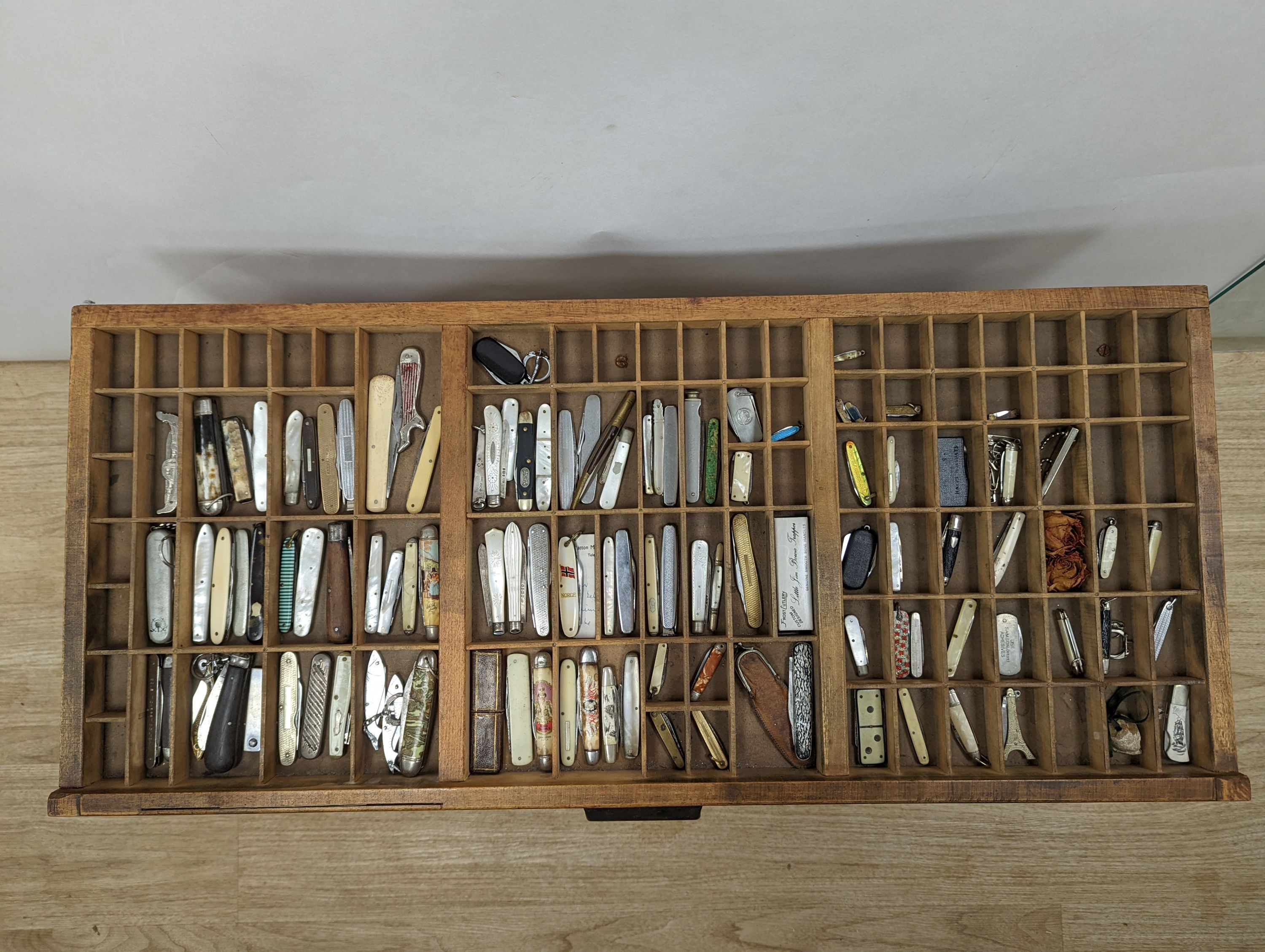 A collection of 19th century and later pen and fruit knives mounted in a coffee table